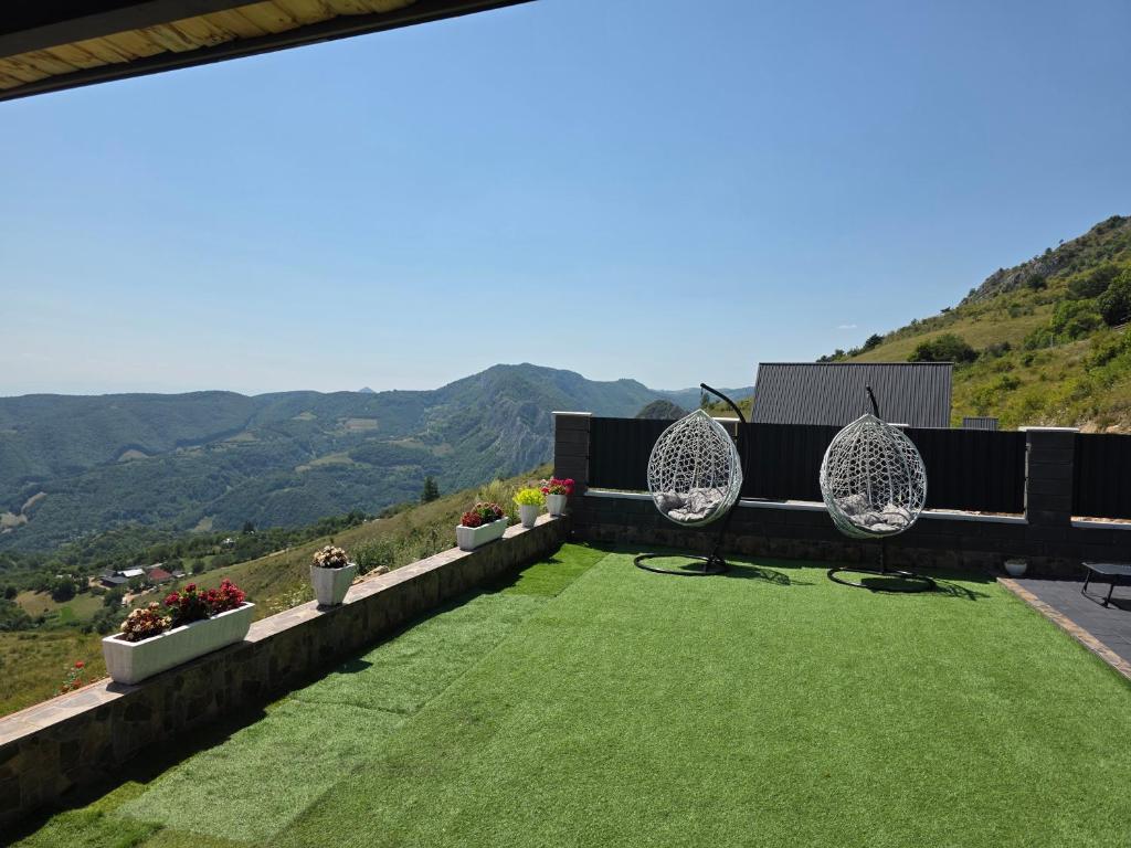 Terasă cu gazon, două fotolii-leagăn și panorama dealurilor