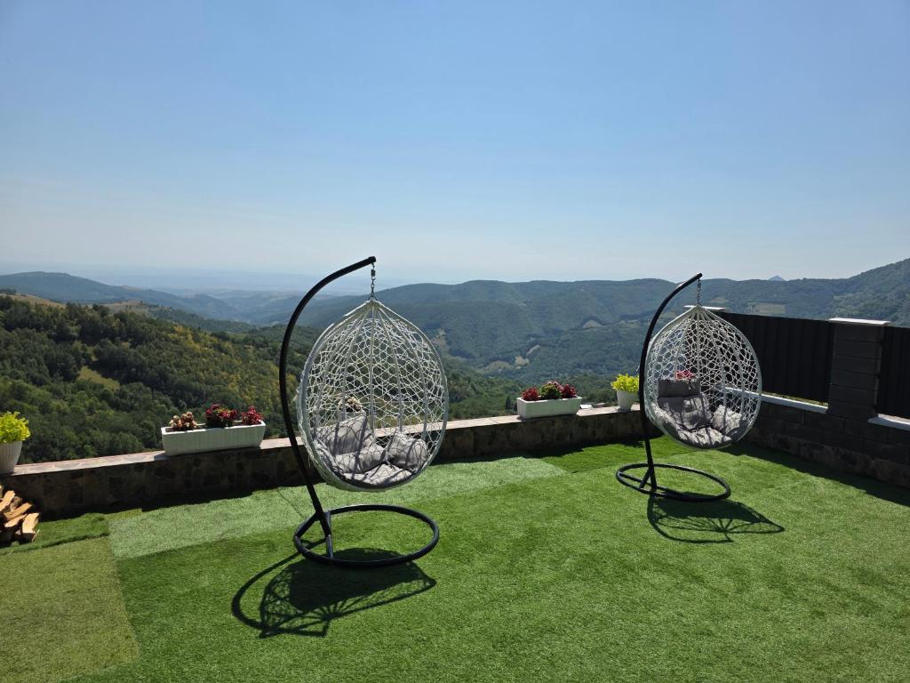 Terasă cu fotolii-leagăn, flori pe parapet și lemne de foc stivuite